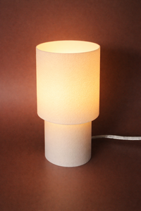 Small table lamp with a white shade on a brown background