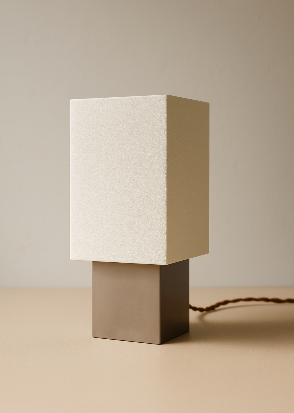 Minimalist table lamp with a beige square shade on a matching base against a beige background